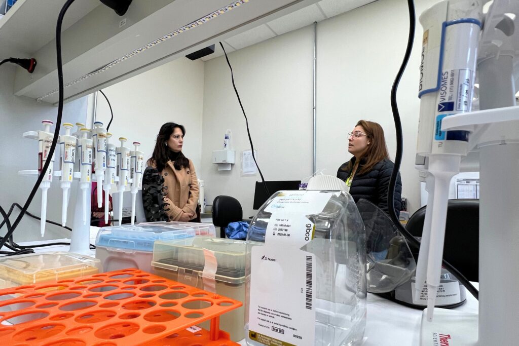 Secretária Mila Corrêa observa explicação de pesquisadora em laboratório do CTVacinas